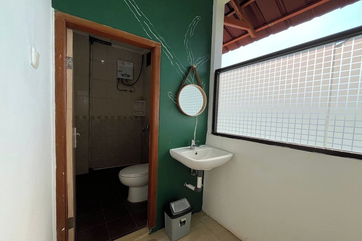 A bathroom with a green wall, a white sink, and a toilet.