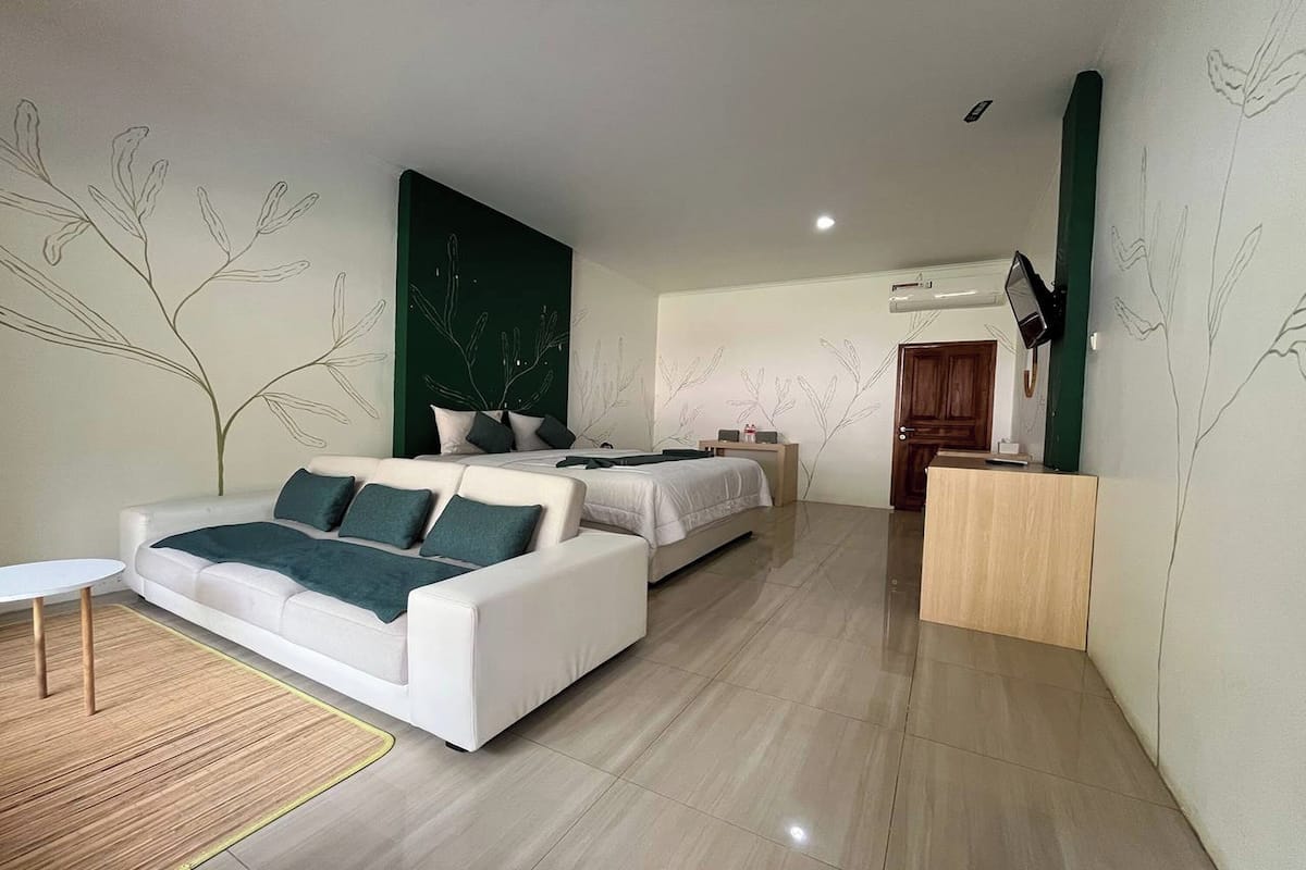 Una habitación de hotel moderna con sofá, cama, escritorio y televisión.