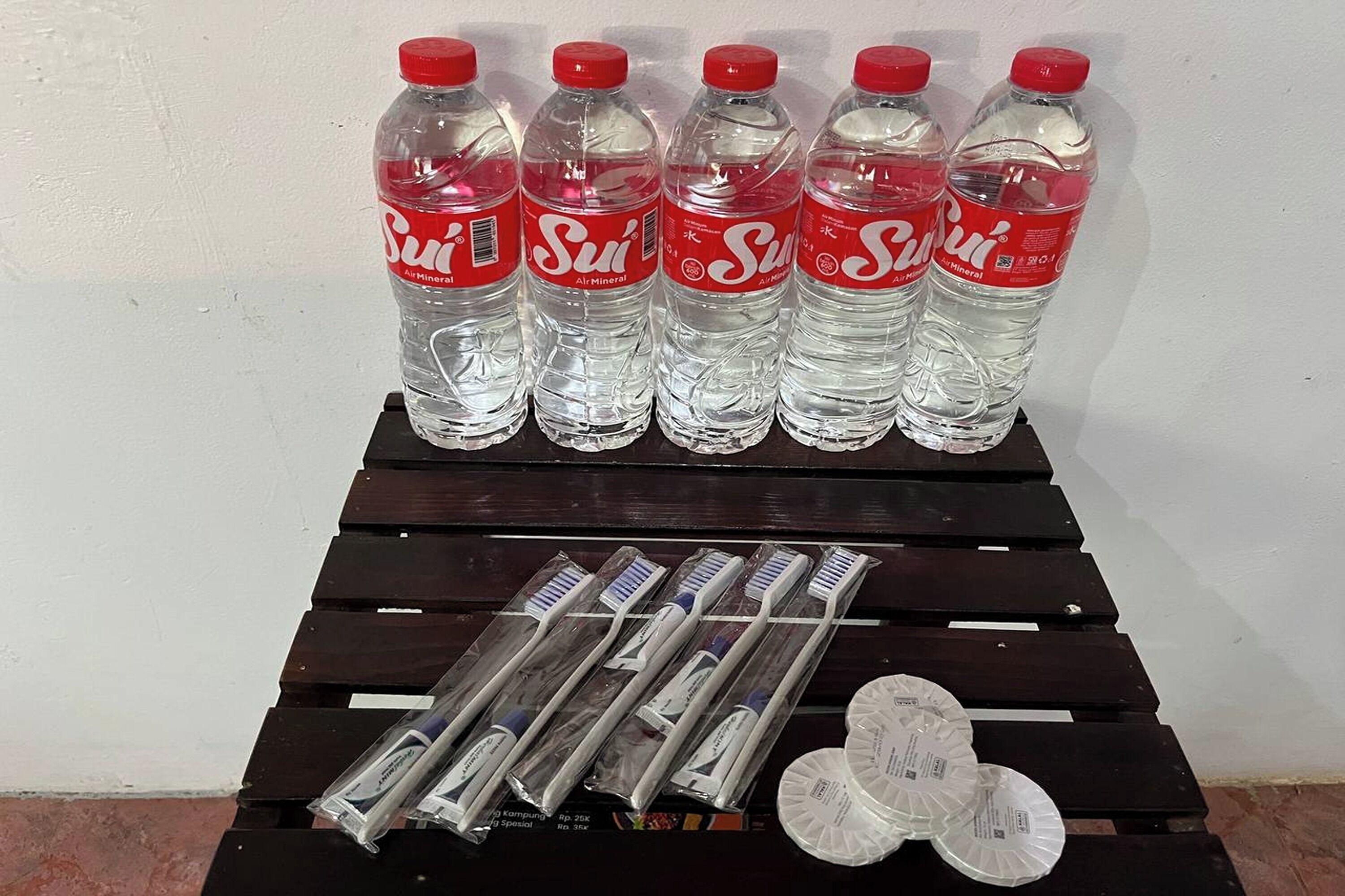 Six bottles of Sui Air Mineral water and several toothbrushes on a wooden table.