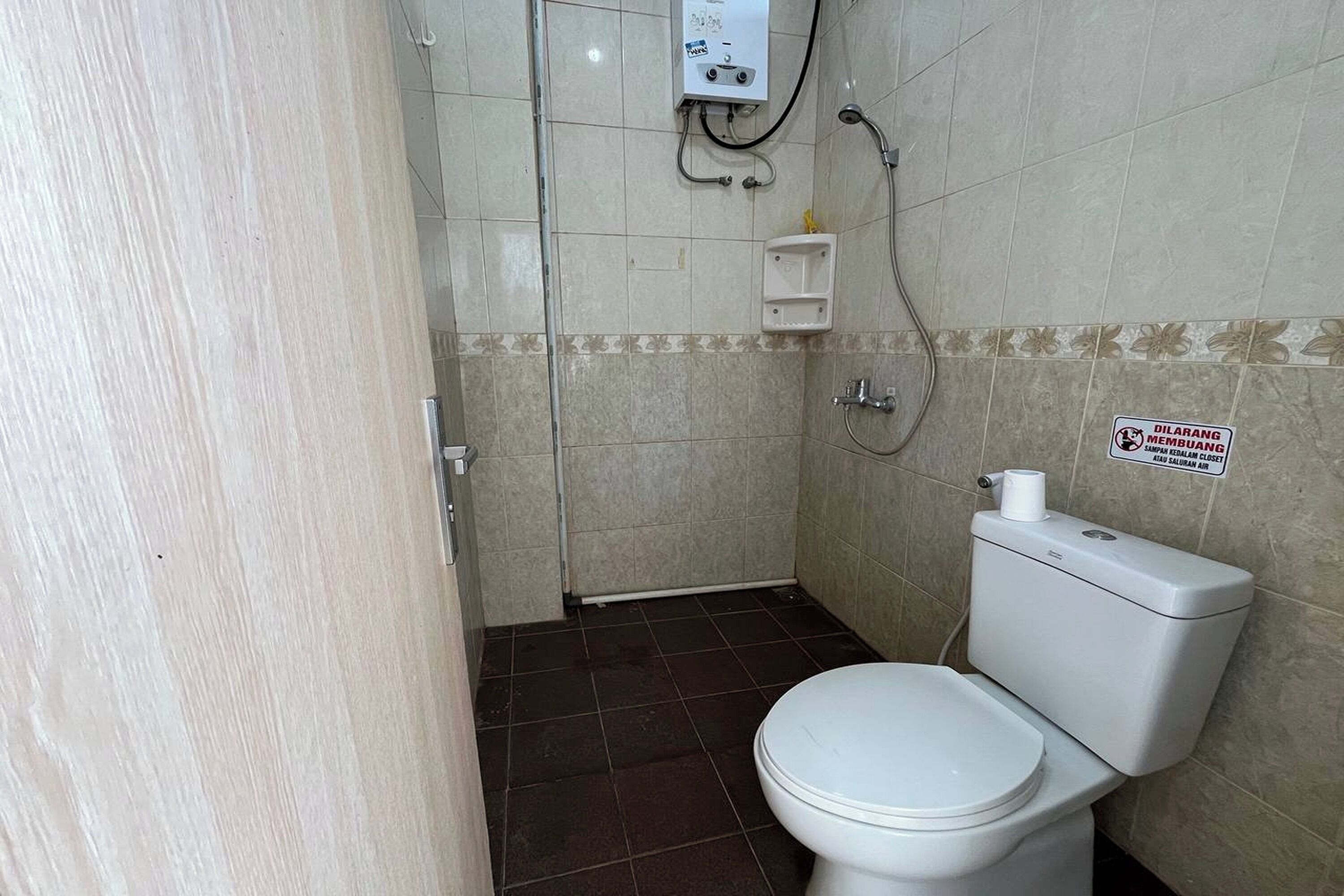 A bathroom with a toilet, shower, and a sign on the wall.