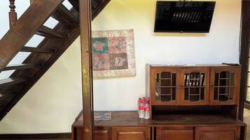 A wooden staircase leading to a landing with a cabinet and a television mounted on the wall.