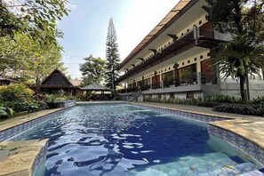 A swimming pool with a tiled edge, surrounded by a building with balconies and a covered area. - Santa Monica Resort (Caringin)