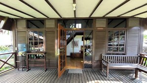 A wooden deck with a bench and a table, a door leading to an interior space, and a water tank outside. - Santa Monica Resort (Caringin)