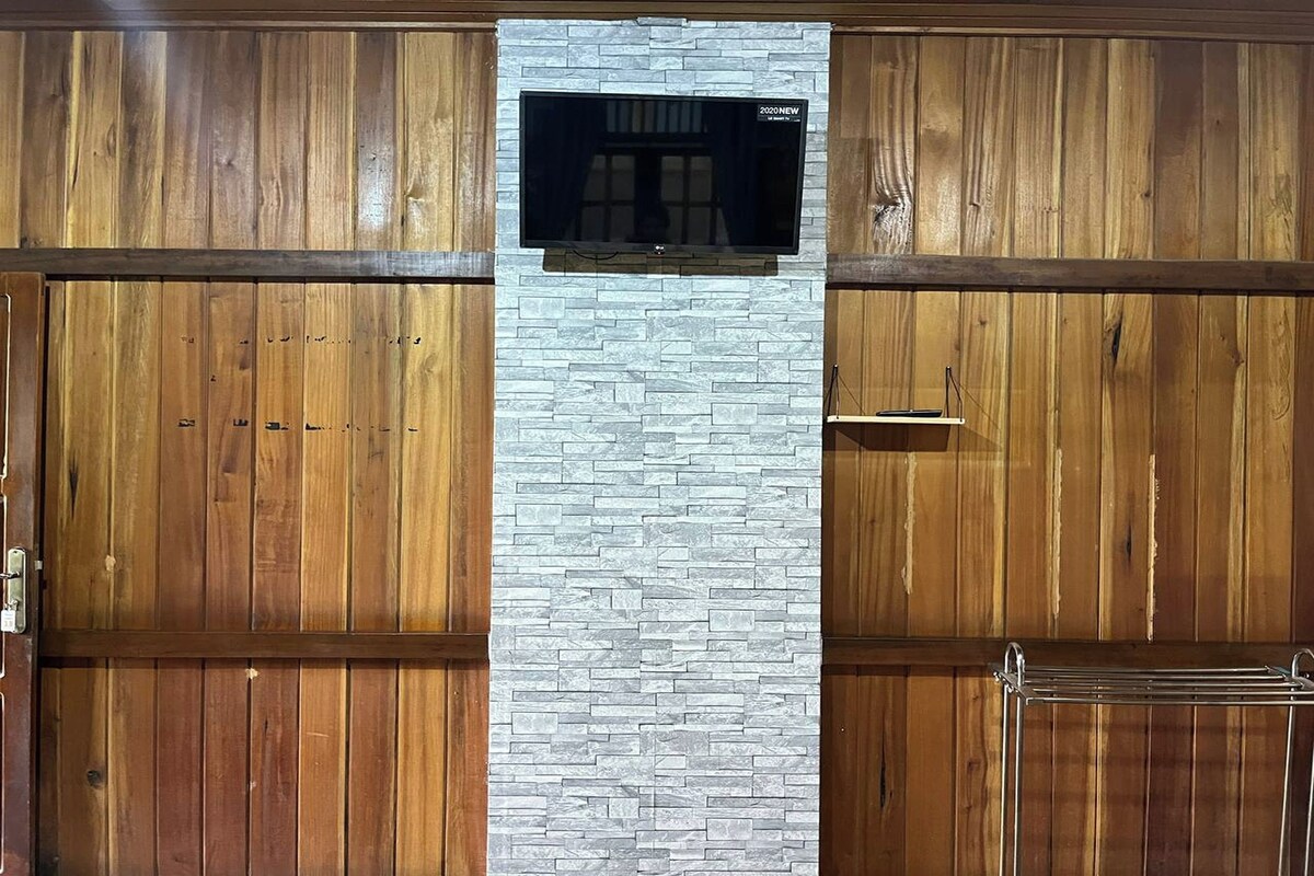 A room with wooden panel walls, a stone accent wall, and a mounted flat-screen TV.