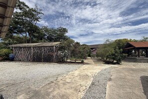 Un patio con un mirador, un pequeño jardín y un edificio con tejado de baldosas.