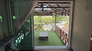 A room with a sliding glass door leading to an outdoor balcony with a table and chairs. - Inapan Taman Herba (Kepala Batas)
