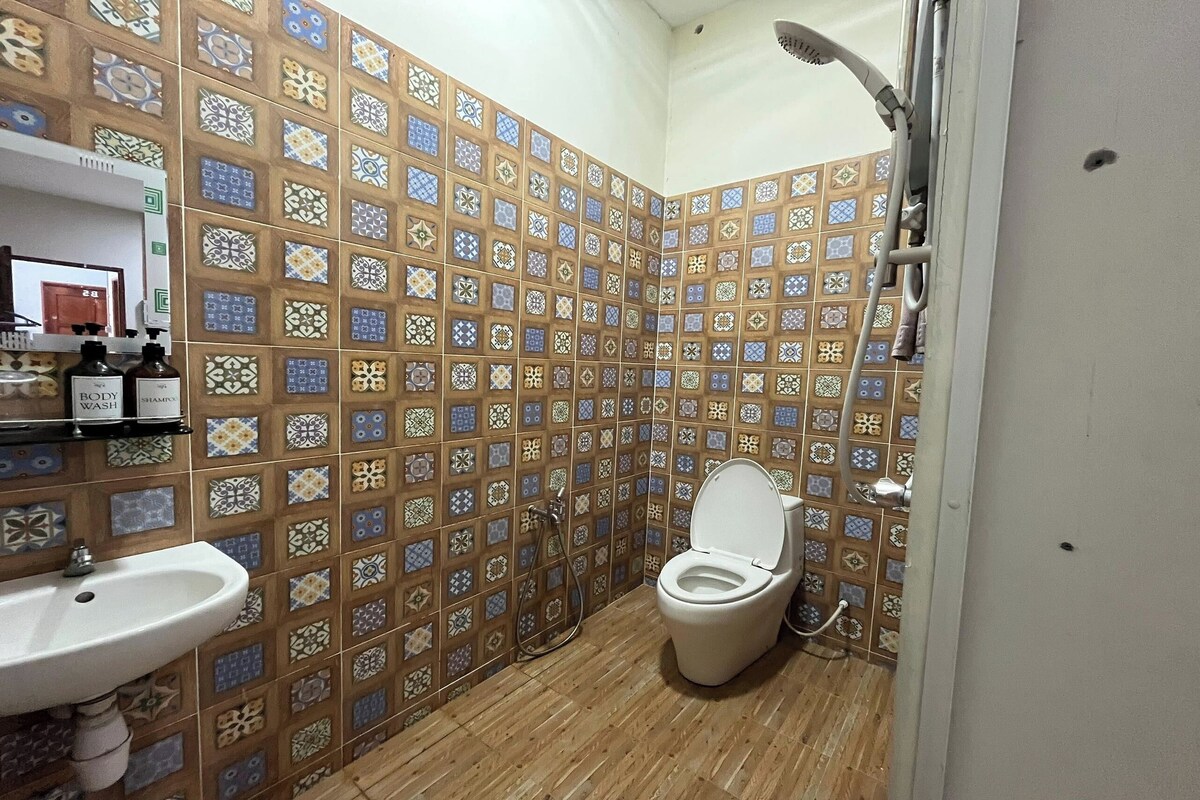 A bathroom with a tiled wall, a sink, a toilet, and a shower.