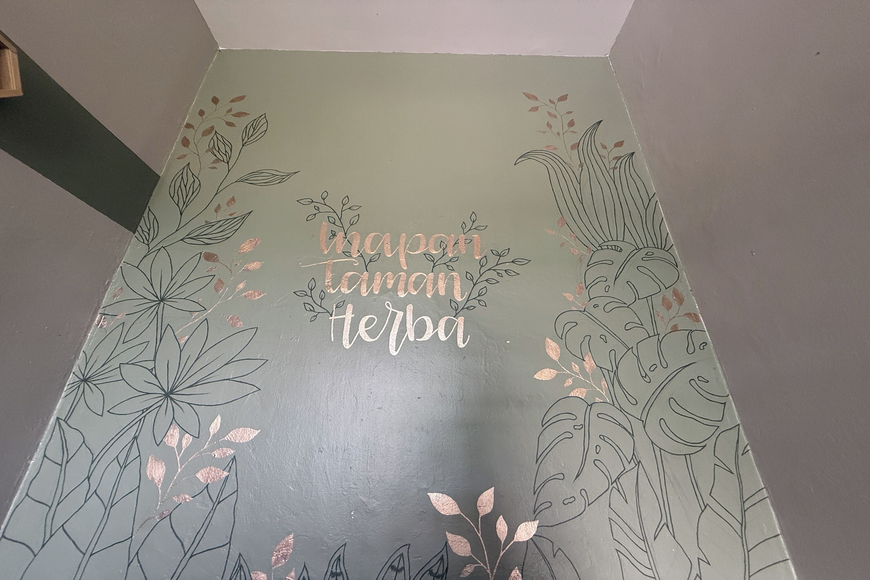 A wall with a floral design and the text "napan taman herba".
