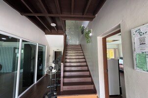 A staircase with wooden steps leading to a room with a bed and a fan.