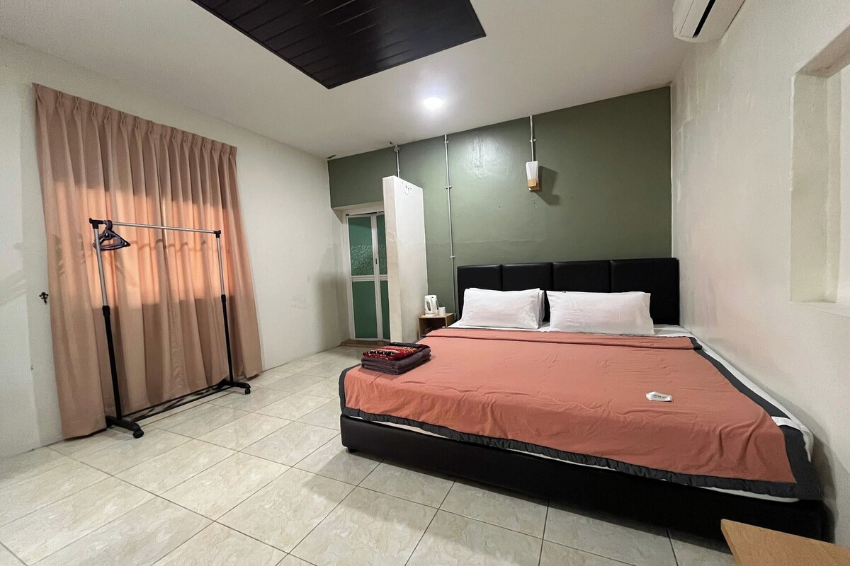 A hotel room with a bed, a wardrobe, a curtain, and a ceiling light.