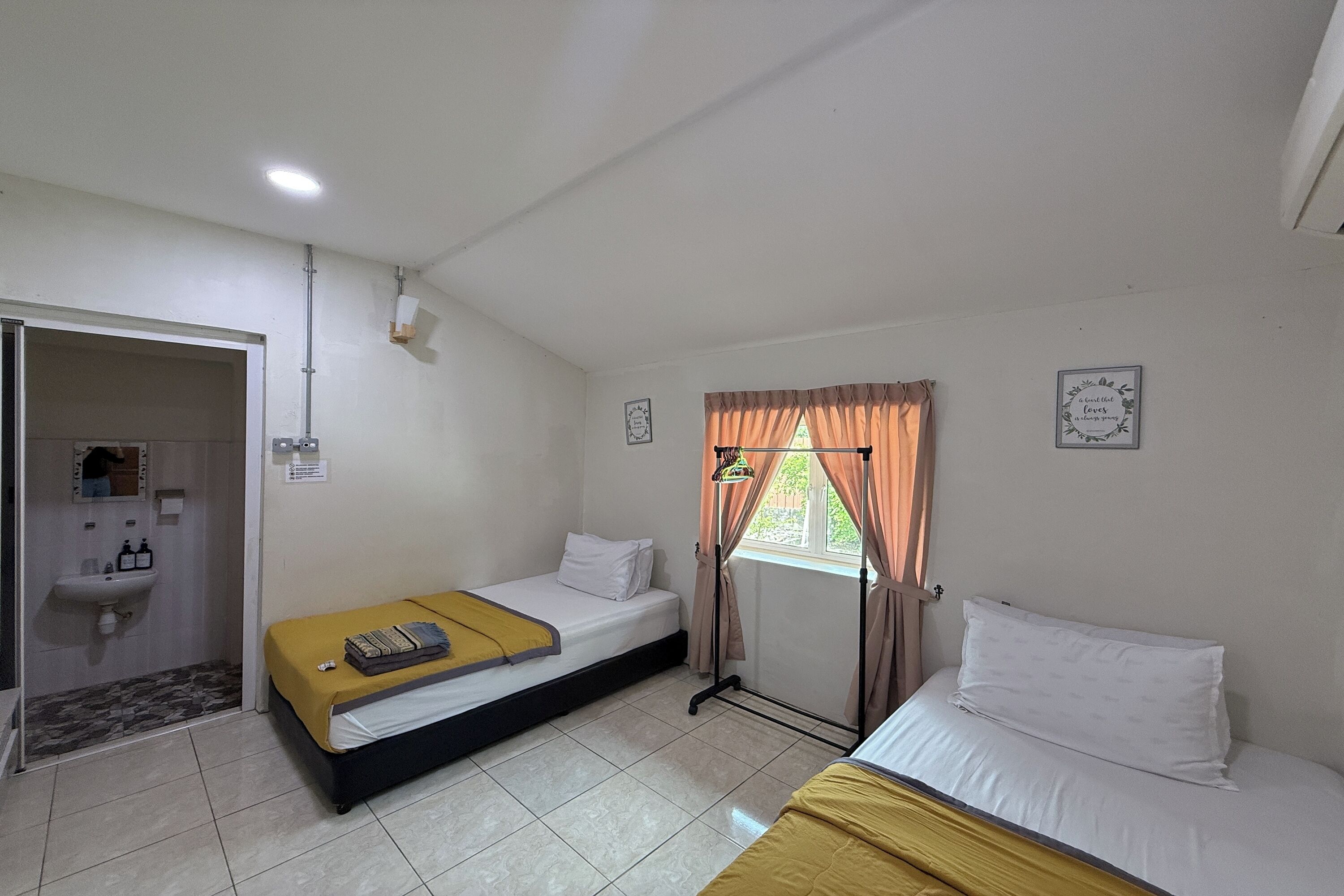 A room with two beds, a sink, and a window with curtains.