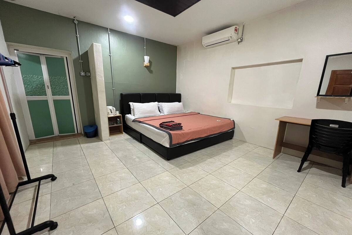 A bedroom with a bed, bedside table, and a desk with a chair.