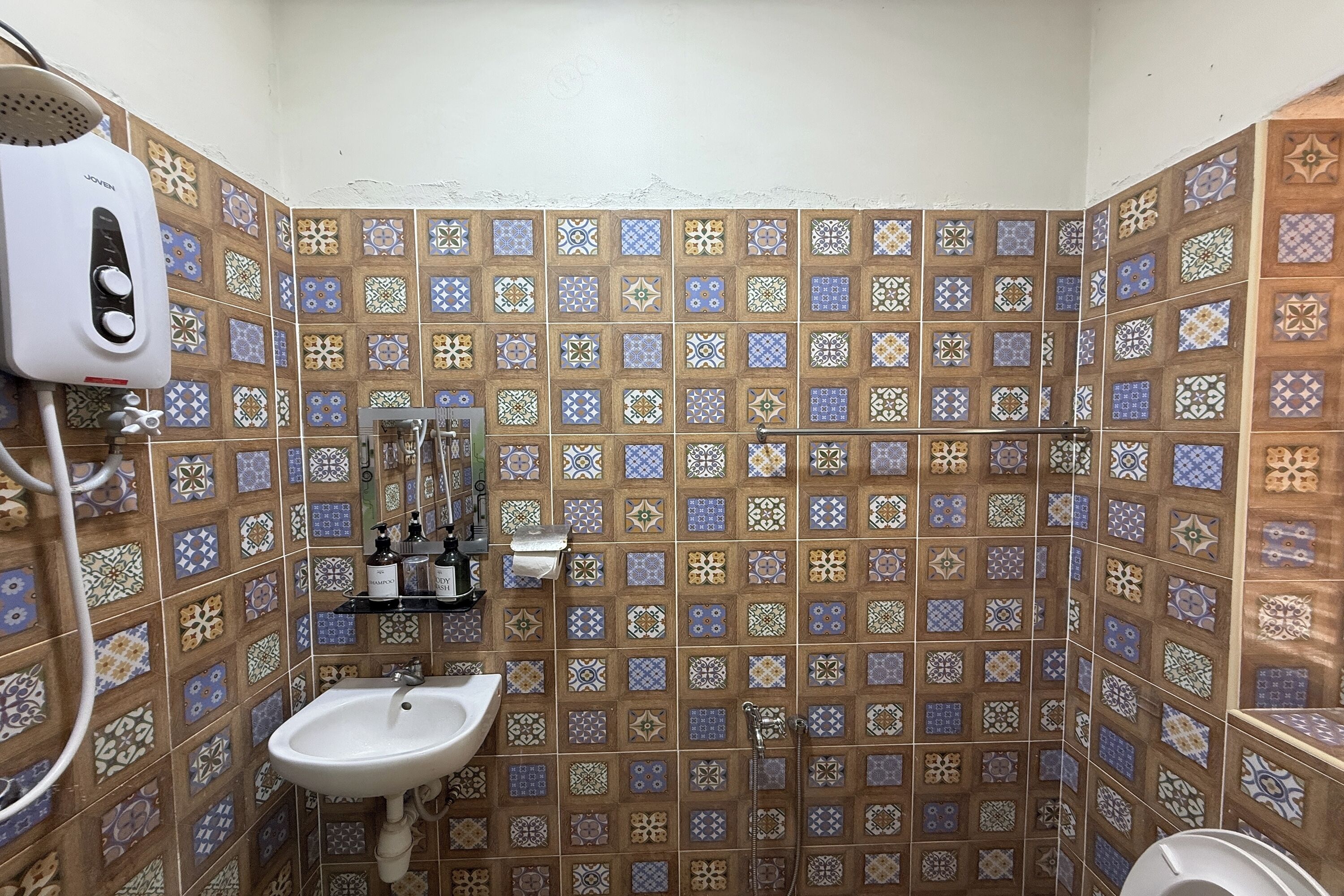 A bathroom with patterned tiles, a sink, a hairdryer, and a shower.