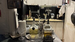 Ett kök med vita skåp, en diskho och diverse köksredskap, inklusive en flaska Jack Daniel’s-whisky, en kaffebryggare och en glasskål.