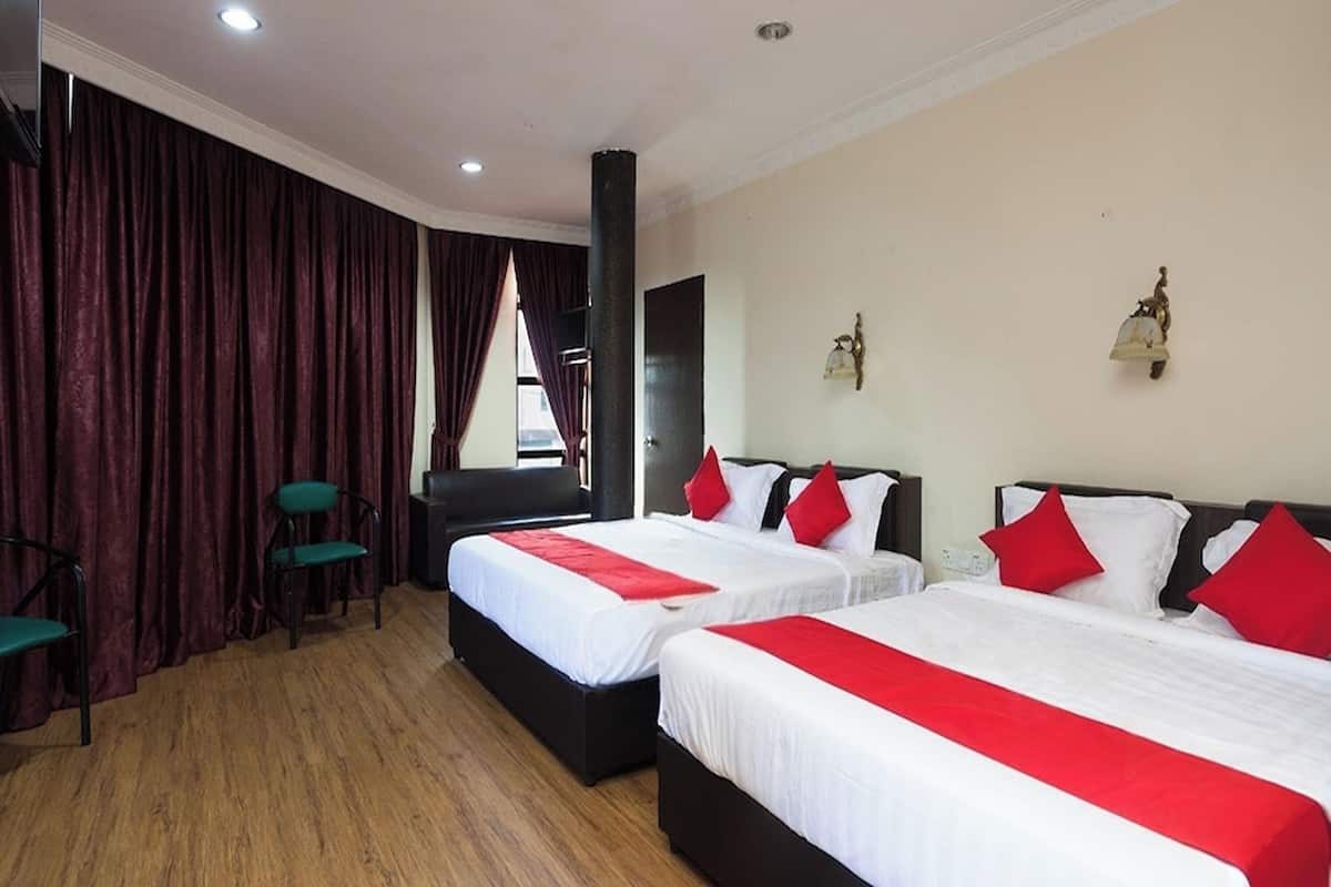 Ein Hotelzimmer mit zwei Betten, roter und weißer Bettwäsche, Holzboden und Blick ins Freie durch ein Fenster.