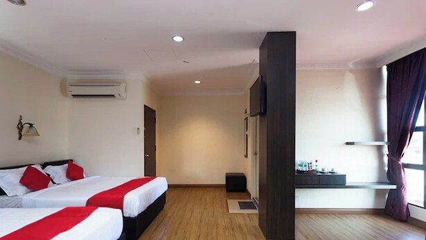A hotel room with two beds, a flat-screen TV, an air conditioning unit, and a window with curtains. - T P Hotel (Sitiawan)