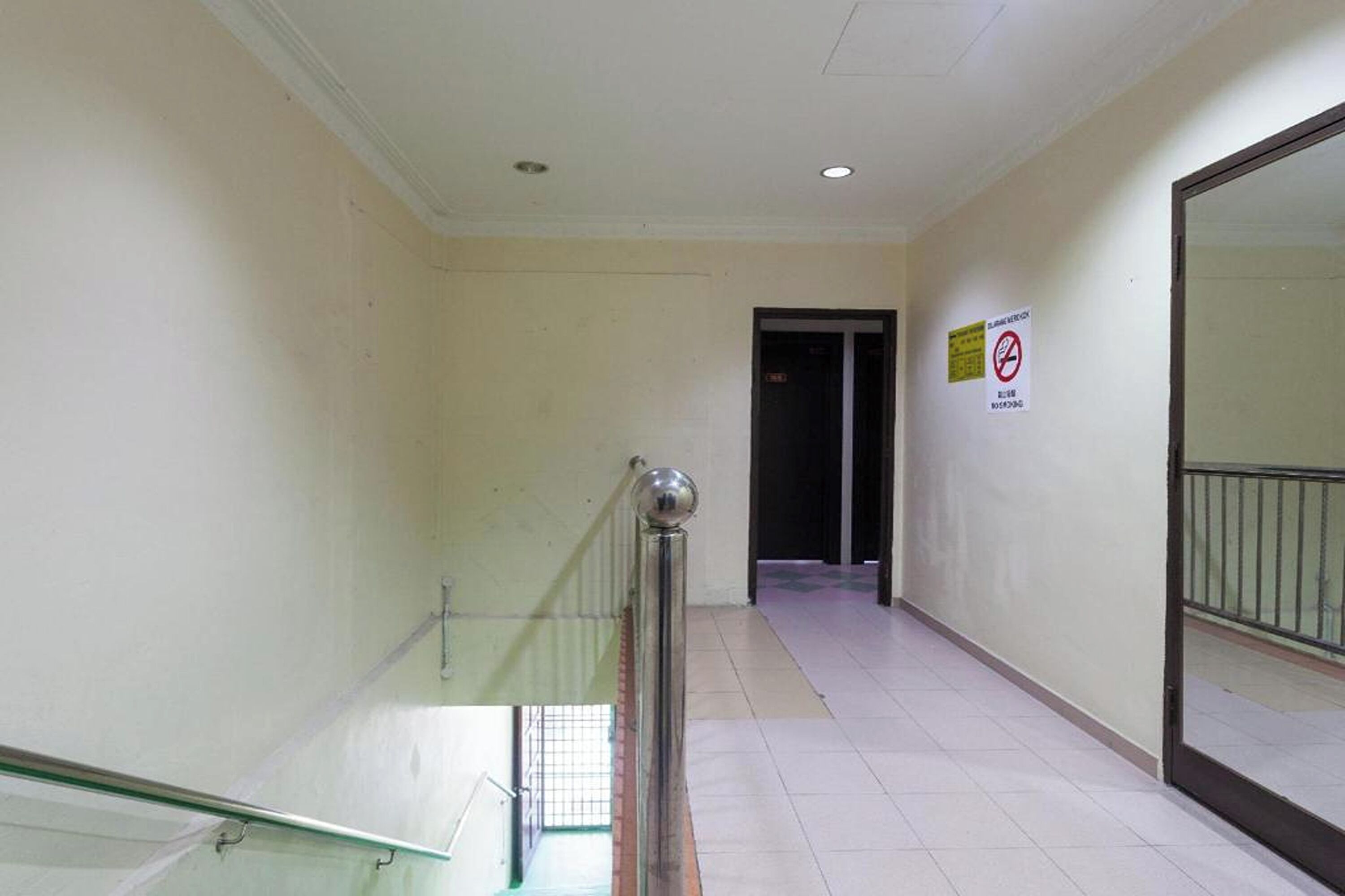 A corridor with a glass railing, a door at the end, and a no-smoking sign on the wall.