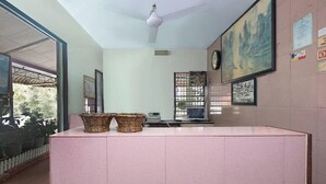 Un área de recepción con mostrador, dos cestas de mimbre, un reloj y cuadros en la pared.