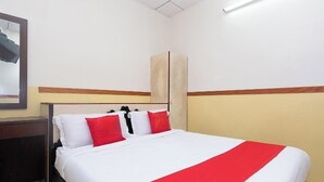 Habitación de hotel con cama, mesita de noche, espejo y lámpara de pared.