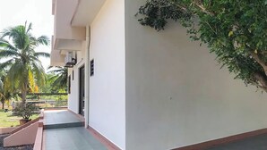 Un edificio con techo plano, un espacio exterior pequeño con un sendero empedrado y una palmera.