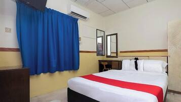 Een hotelkamer met een bed, een bureau, een stoel, een spiegel en een raam met blauwe gordijnen.