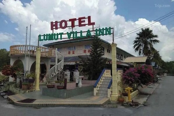 Un hôtel appelé «Hotel Cuntut Villa Inn», avec une enseigne bien visible, un escalier menant à l’entrée et des plantes en pot disposées autour du bâtiment.