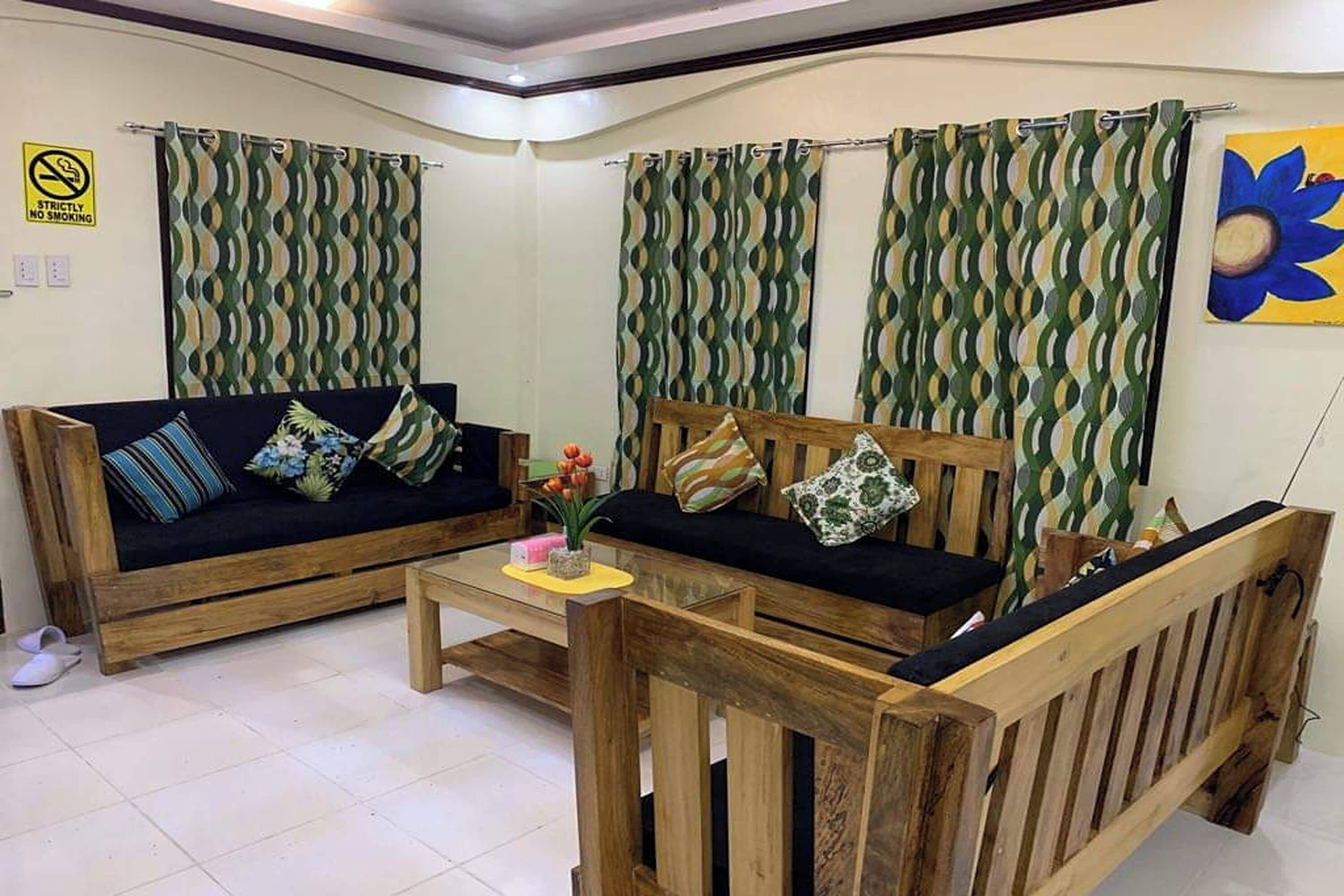 A room with two wooden sofas, a small table, and patterned curtains.