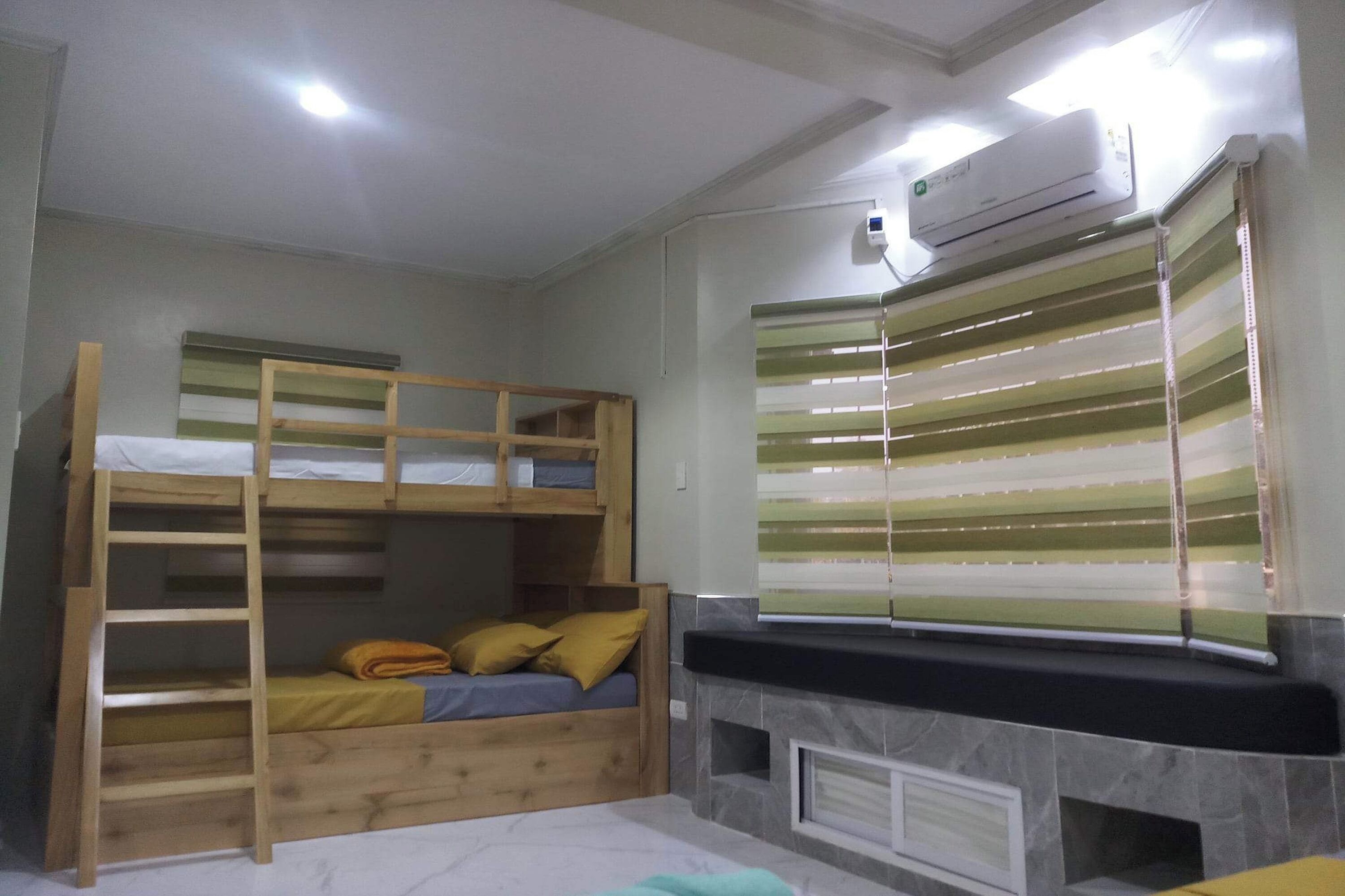 Een slaapkamer met stapelbed, een open haard, gestreepte gordijnen en een airconditioning.