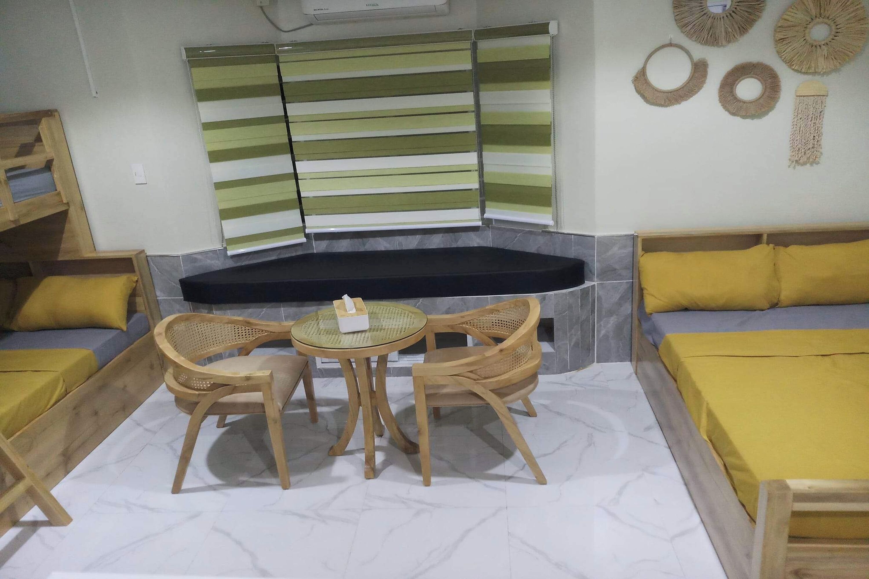 A cozy room with a sofa, a small table with chairs, and a window with striped blinds.