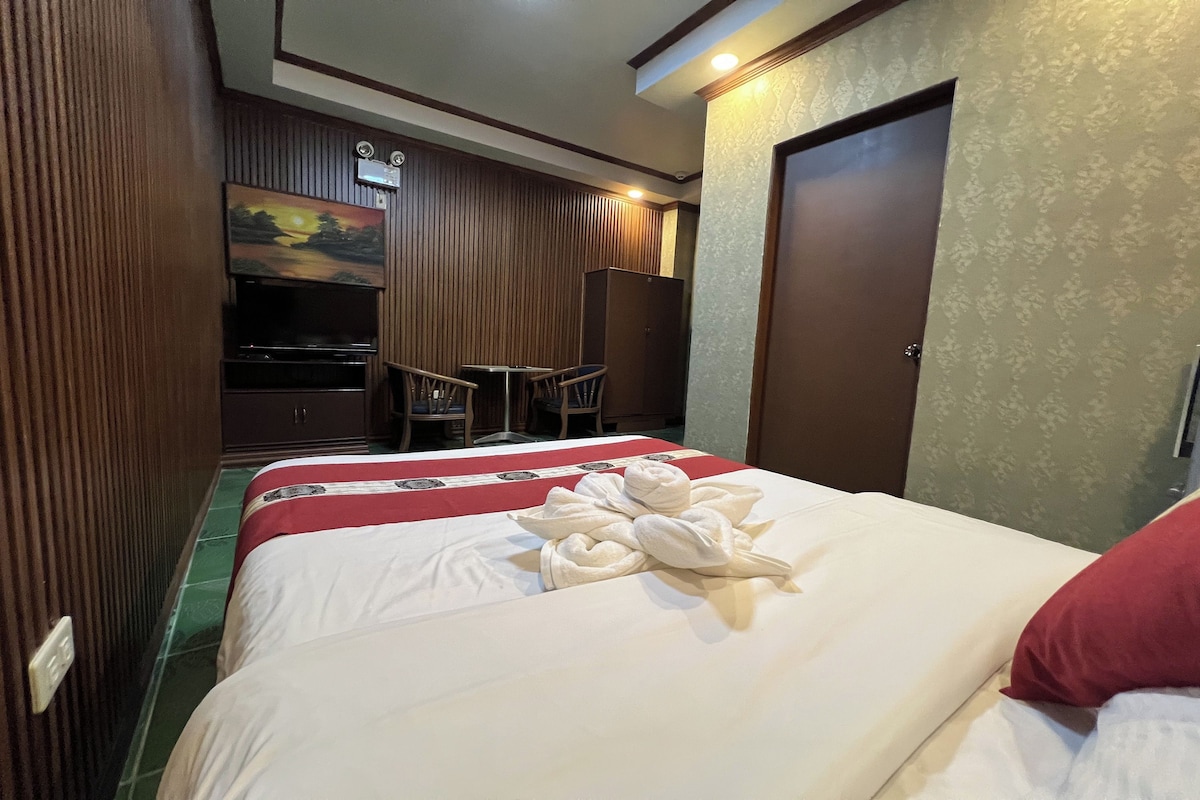 Habitación de hotel con cama, televisión, armario y escritorio con sillas.