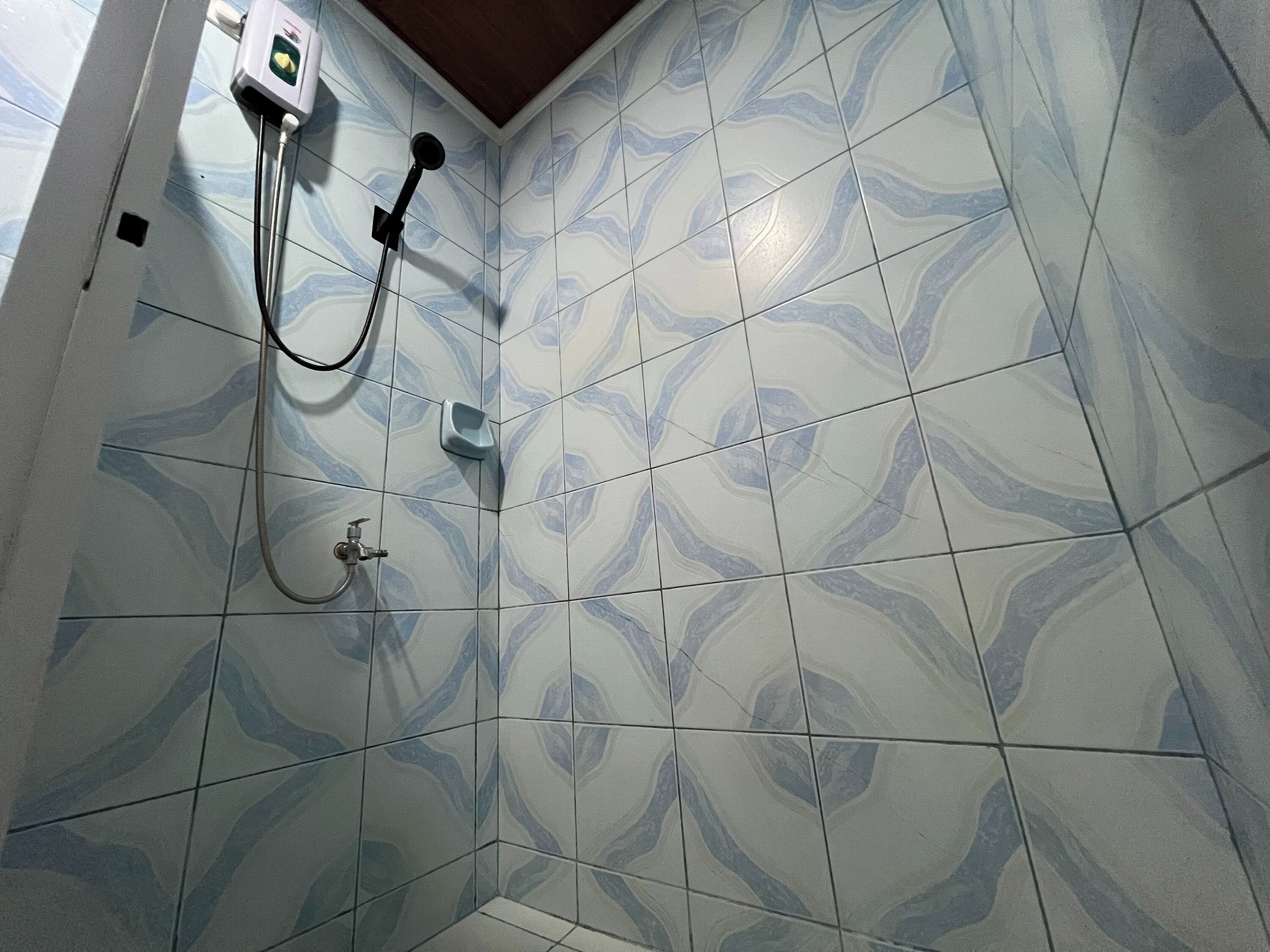 Zona de ducha con pared de baldosas de diseño de mármol, cabezal de ducha manual y grifo empotrado.