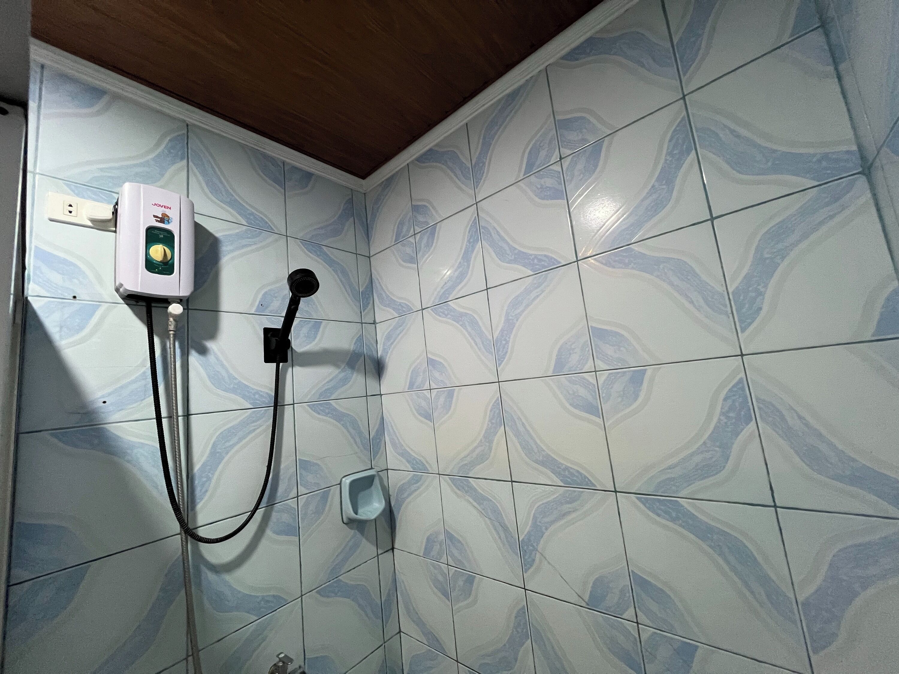 Une salle de bain équipée d’une douche, d’un sèche-mains et d’un distributeur de savon mural.