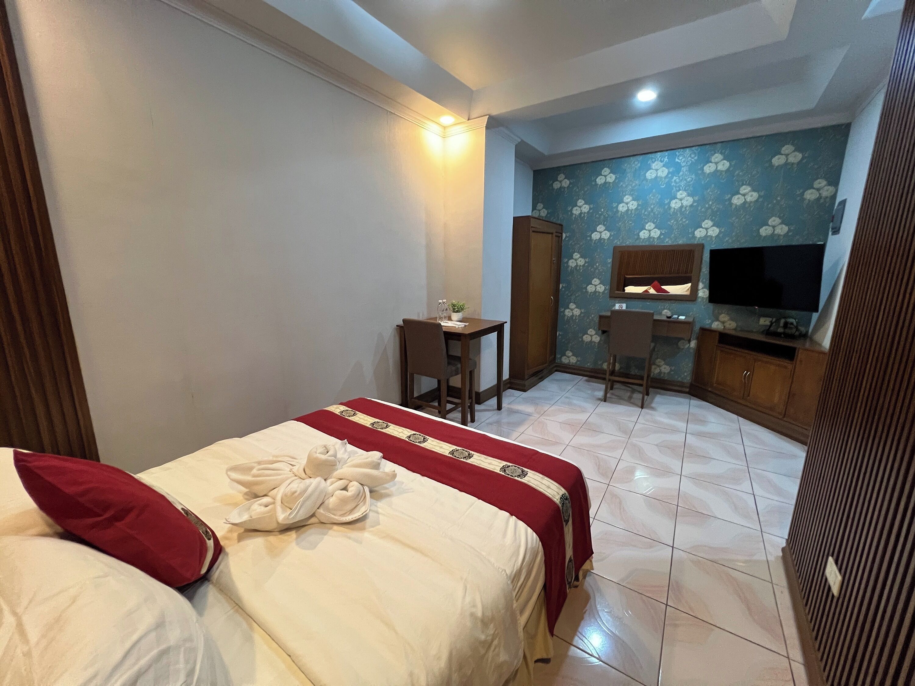 A hotel room with a bed, a desk, a chair, a television, and a wardrobe.