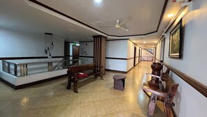 A spacious hallway with a wooden bench, a small stool, and a decorative table. - Rossa Hotel Clark near Airport (Angeles City)