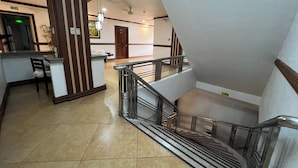 A hotel lobby with a reception desk, a staircase, and a view of the upper floor. - Rossa Hotel Clark near Airport (Angeles City)