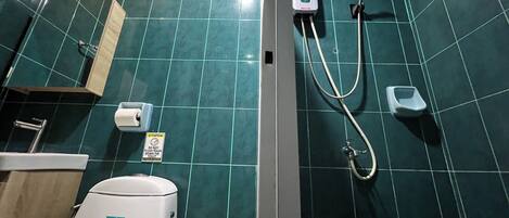 A bathroom with a toilet, a hand dryer, a paper towel dispenser, and a hand soap dispenser.