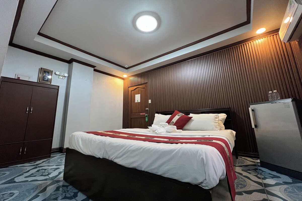 Una habitación de hotel con cama, armario y refrigerador.