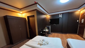 A hotel room with two beds, a desk, a chair, a TV, and a wardrobe. - Rossa Hotel Clark near Airport (Angeles City)