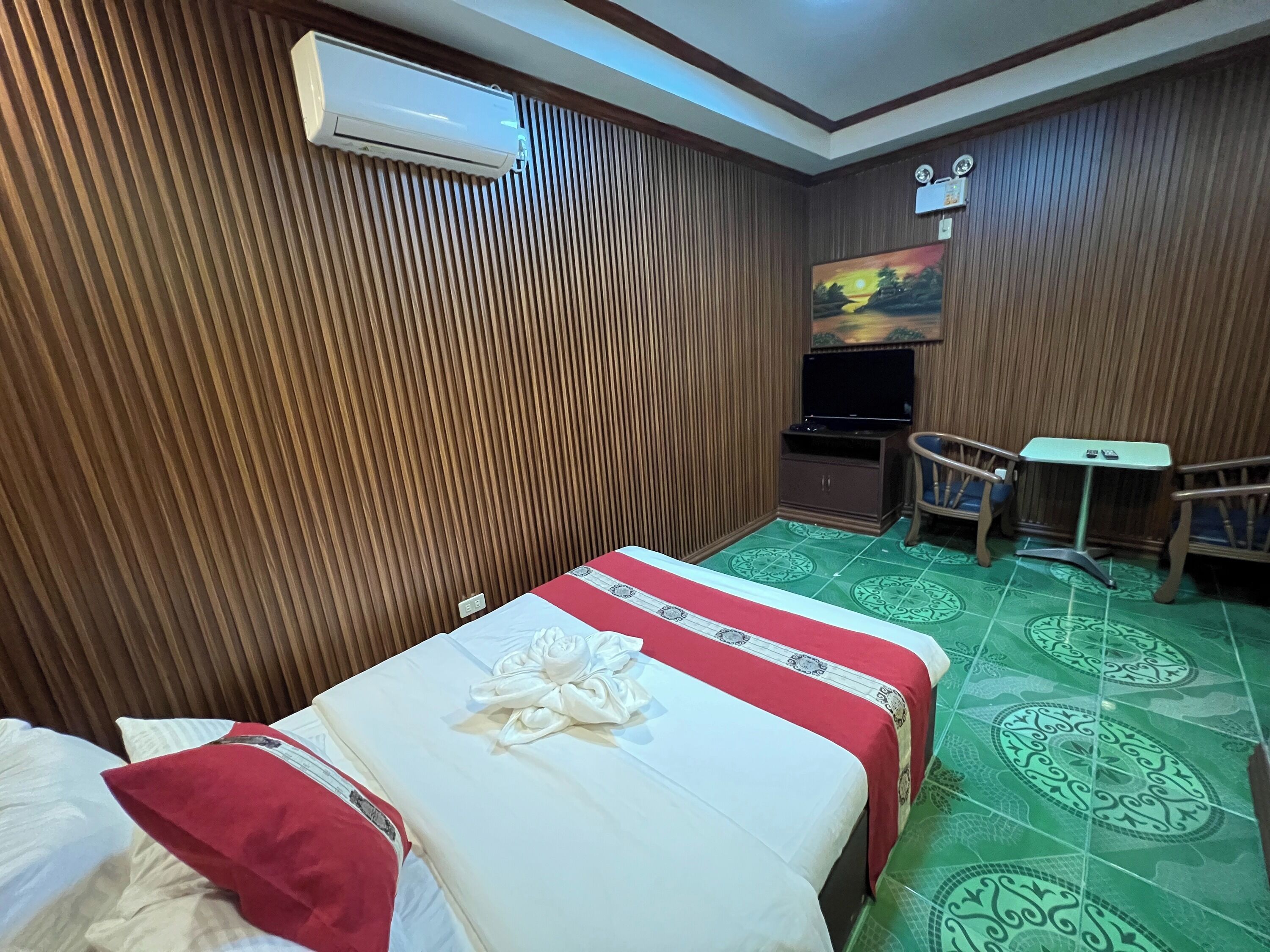 A hotel room with a bed, a small desk, a chair, and a TV.