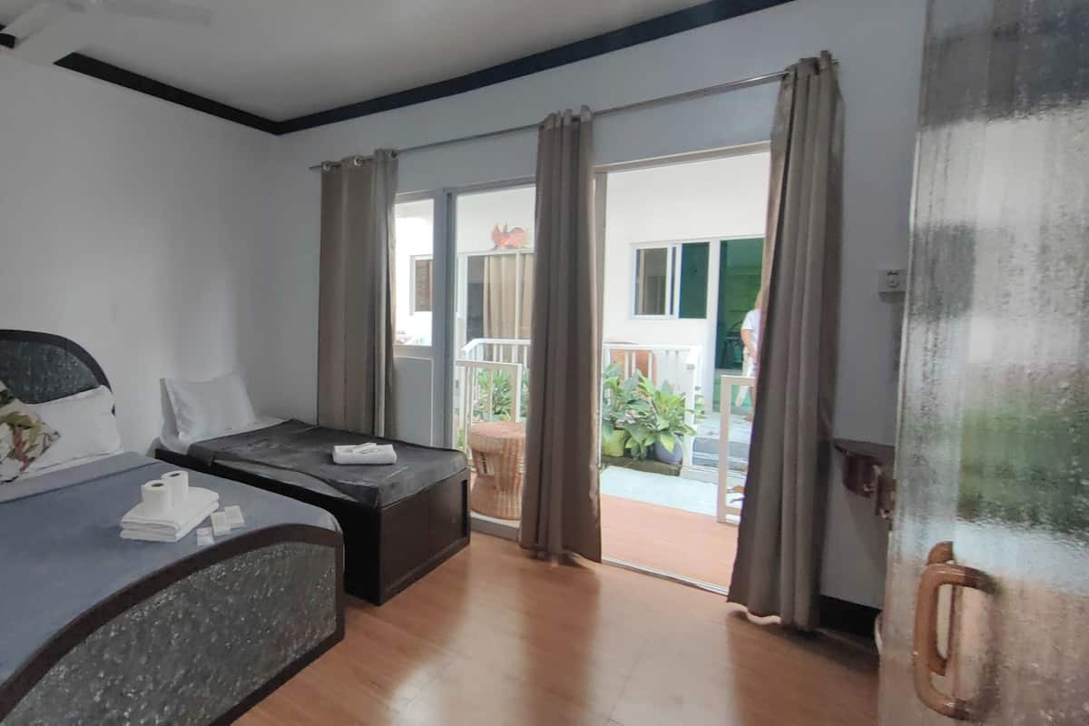 A hotel room with a bed, a small table, and a view of the outside balcony.
