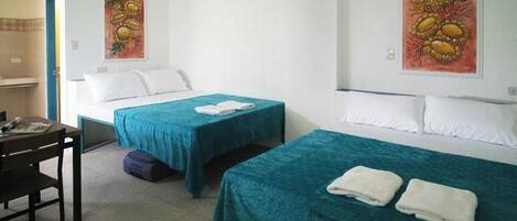 A hotel room with two single beds, a desk, and a chair.