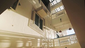 Un intérieur à plusieurs niveaux, doté de balcons, d’un escalier et de luminaires suspendus.