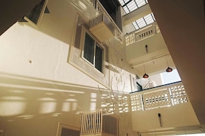 Um interior com vários níveis, varandas, escadaria e luminárias pendentes.