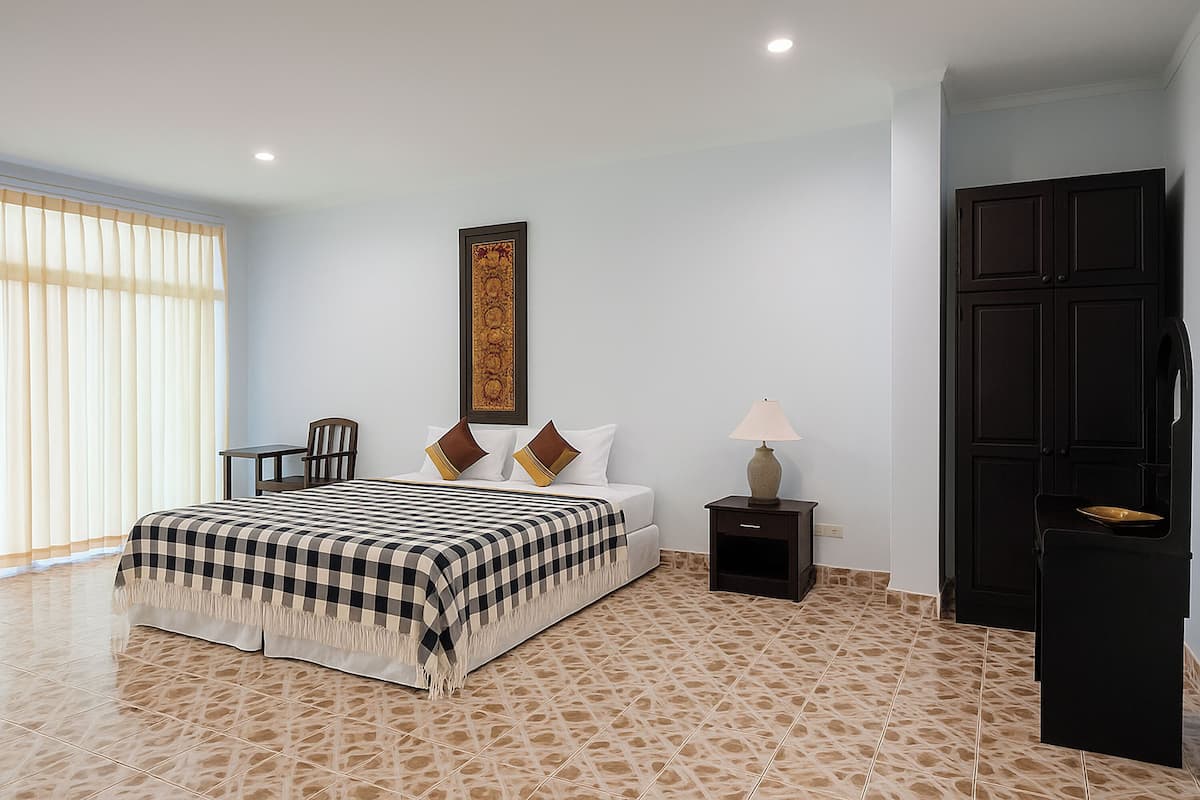 Une chambre d’hôtel avec un lit, une chaise, une table de chevet, une lampe et une armoire.