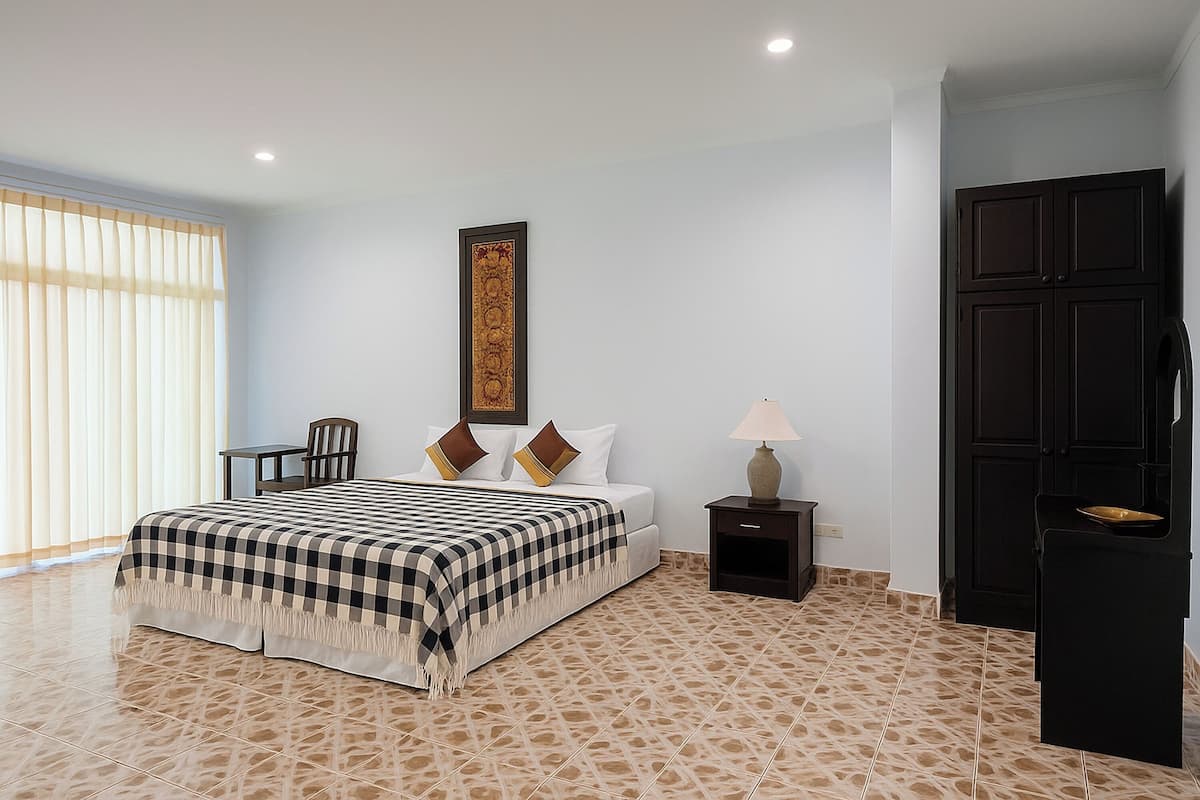 Une chambre à coucher comprenant un lit, une table de chevet, une chaise, une lampe, un tableau encadré et une armoire.