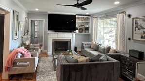 A living room with a fireplace, a ceiling fan, and a television. - A cozy house with best location (Charlotte)