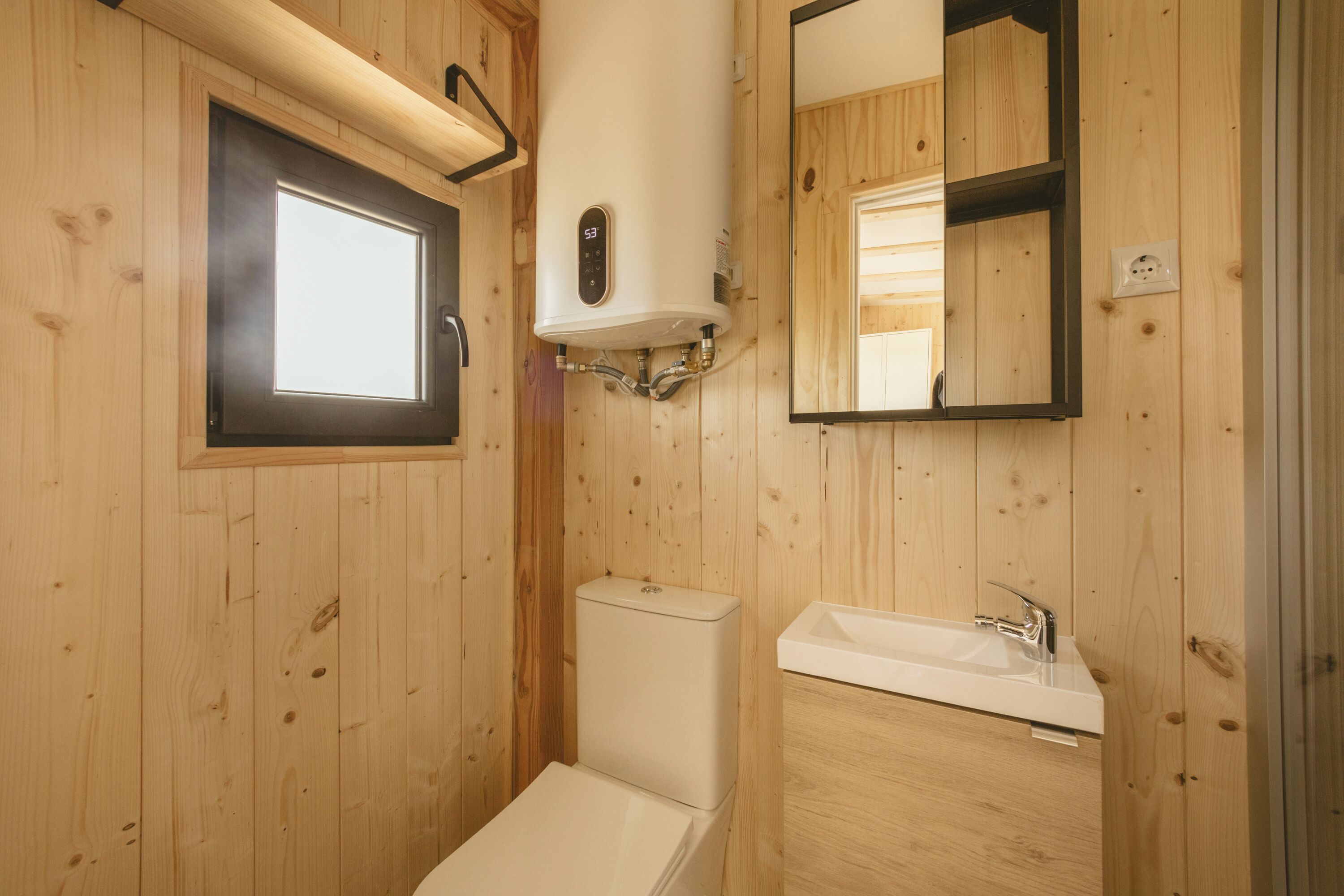 Un baño con paneles de madera, un inodoro, un lavabo y un espejo.