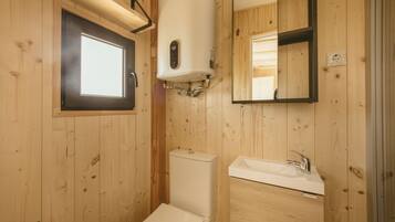 Un baño con paneles de madera, un inodoro, un lavabo y un espejo.