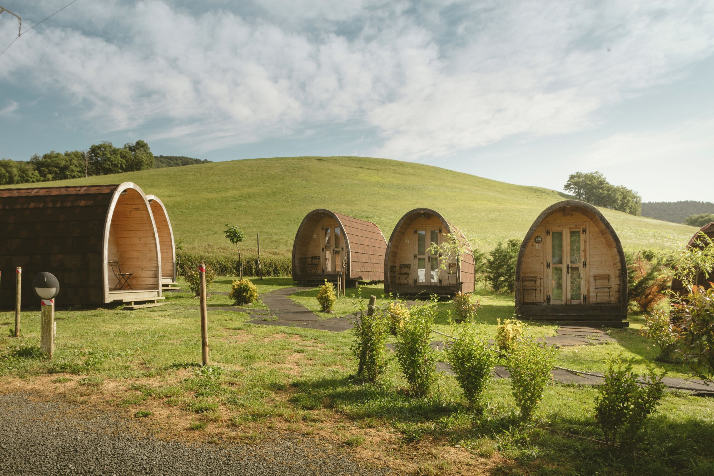 A row of wooden dome-shaped cabins on a grassy hill with a clear sky.