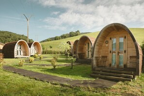 A row of wooden, arched cabins with numbered doors, set in a grassy area with a clear sky. - CAMPING IZARPE (Atez)